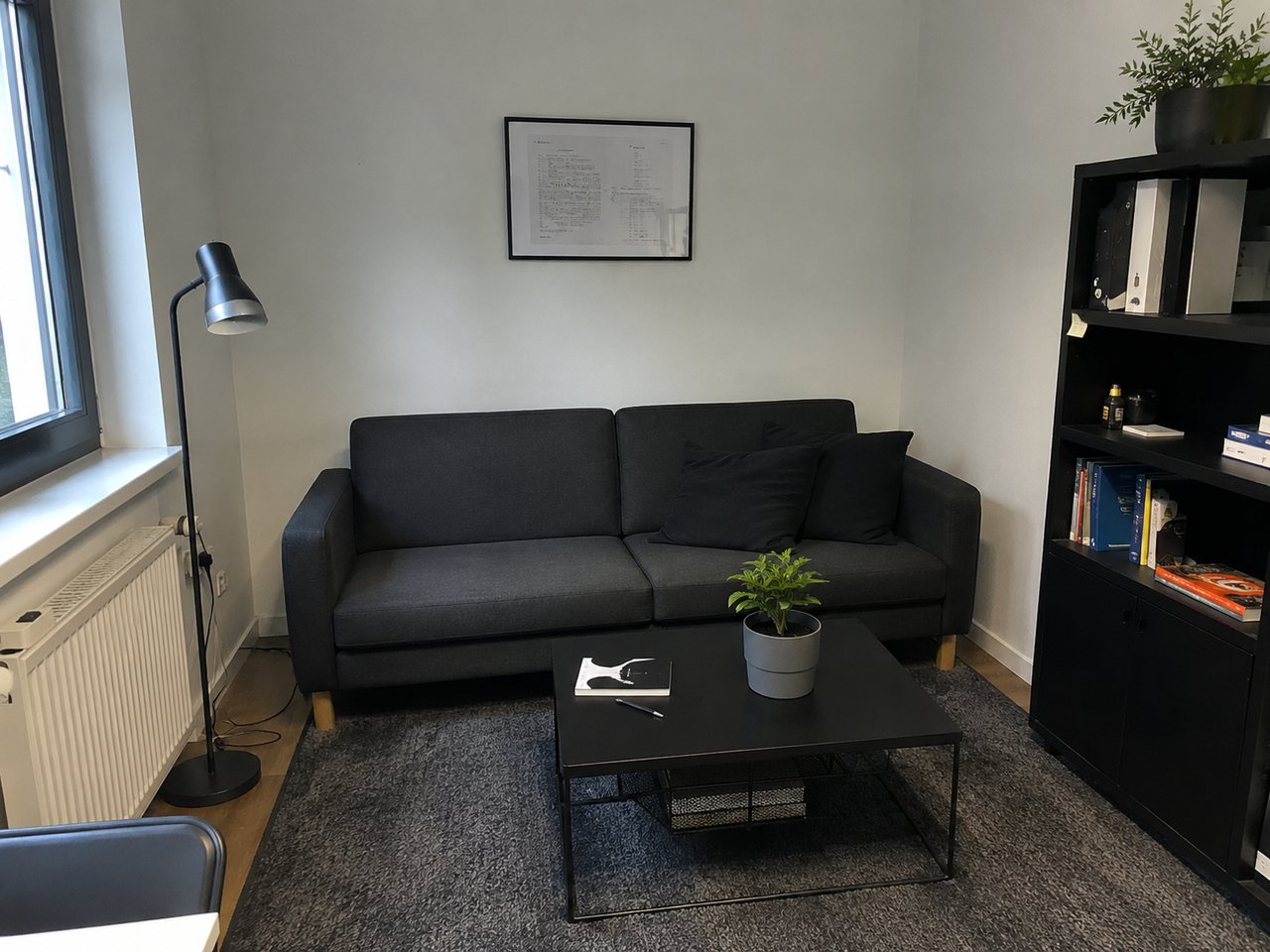Lounge-Ecke im Büro von masesites mit dunklem Sofa, Couchtisch und Regal am Fenster